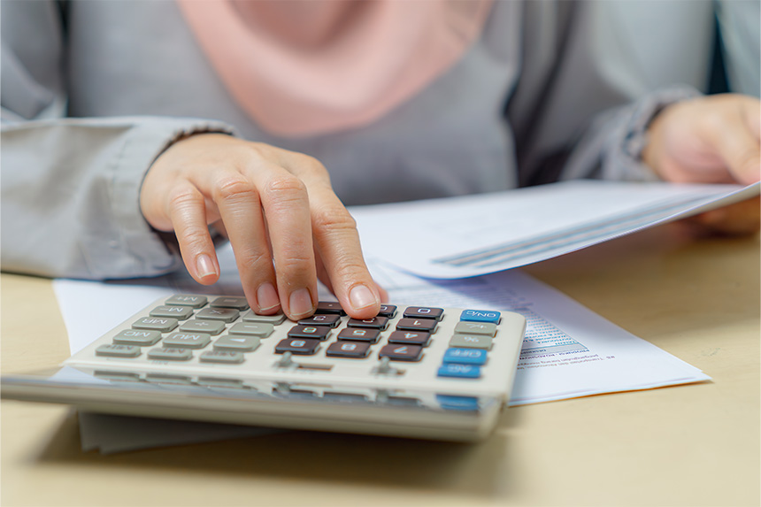 A closeup of a woman pressing the keys on a calculator.] Budgeting is a great way to keep your Christmas spending in check.
