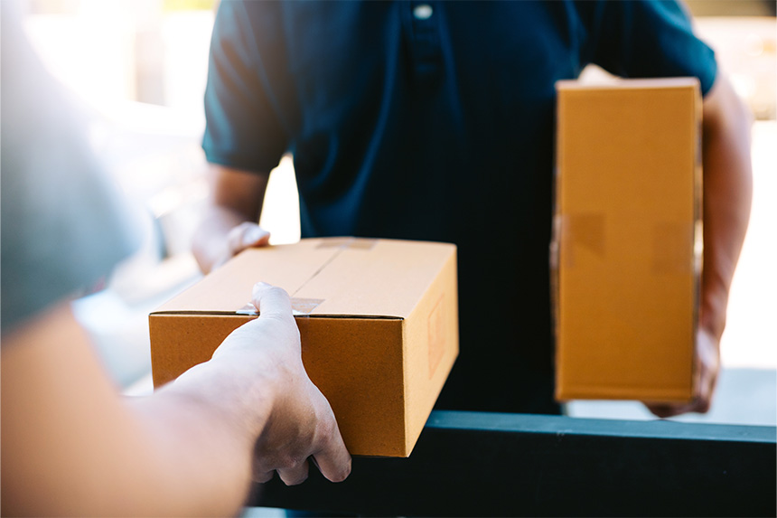 A delivery personnel hands a box package to a customer.