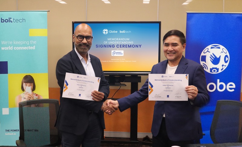 Baldev Singh and Darius Delgado shaking hands at the Globe and bolttech Gadget Xchange signing ceremony.