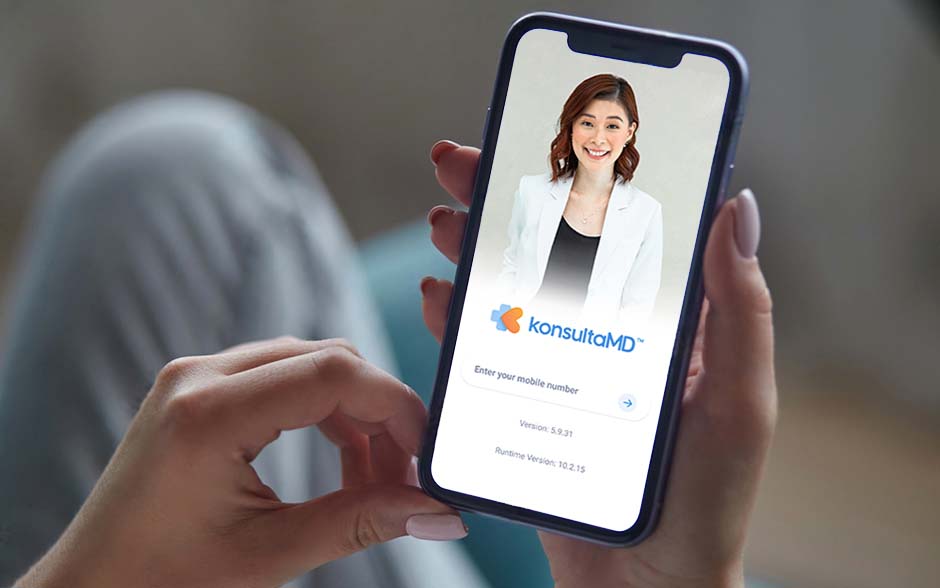 A close-up of a woman holding a smartphone with KonsultaMD App