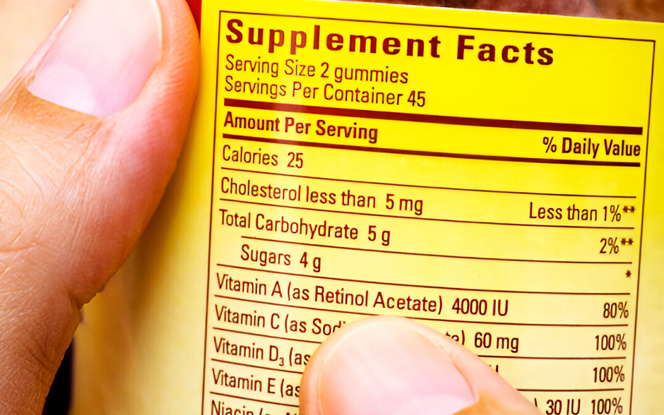 Close-up of a person's hand holding a yellow nutritional information label titled "Supplement Facts."
