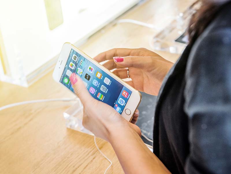 Woman holding iPhone 6 Plus in the Apple store.