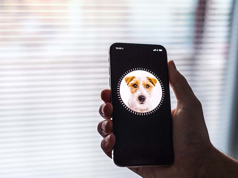 Hand holding iPhone X with face ID technology.