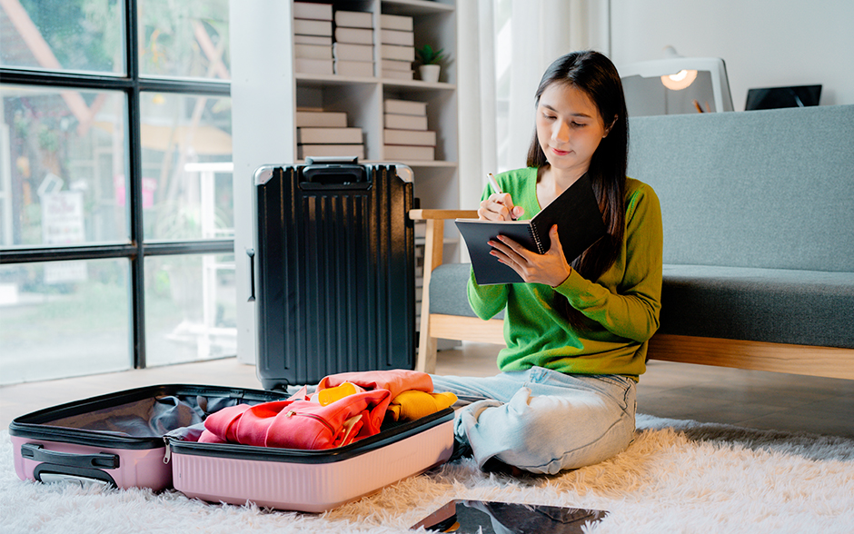 Woman packing her clothes and writing in a notebook.