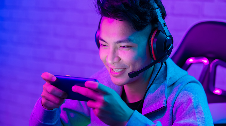 Young Asian man playing on a ranked match on his mobile phone while streaming.