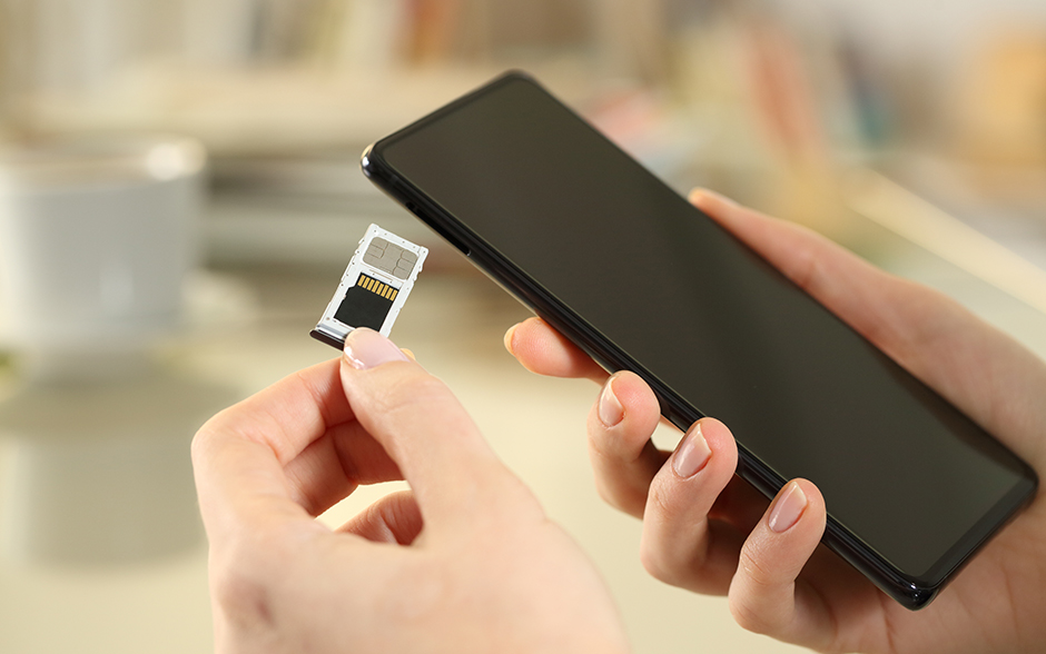 Photo of a girlâs hand inserting a SIM and SD card on a smartphone.