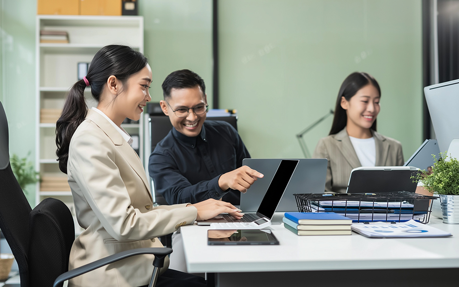 Young Asian colleagues meeting at the office with their laptops open in front of them.