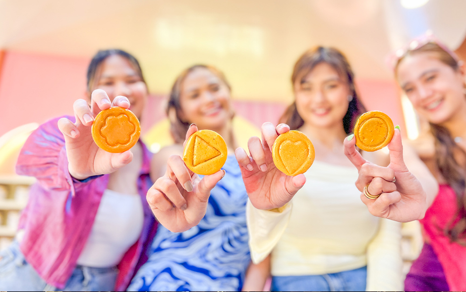 Photo of four young Asian women holding up dalgona candies in the Candy Carnival room.