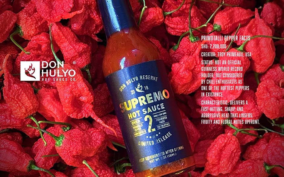 Bottle of Don Hulyo Supremo Hot Sauce placed on a bed of fresh red chili peppers.