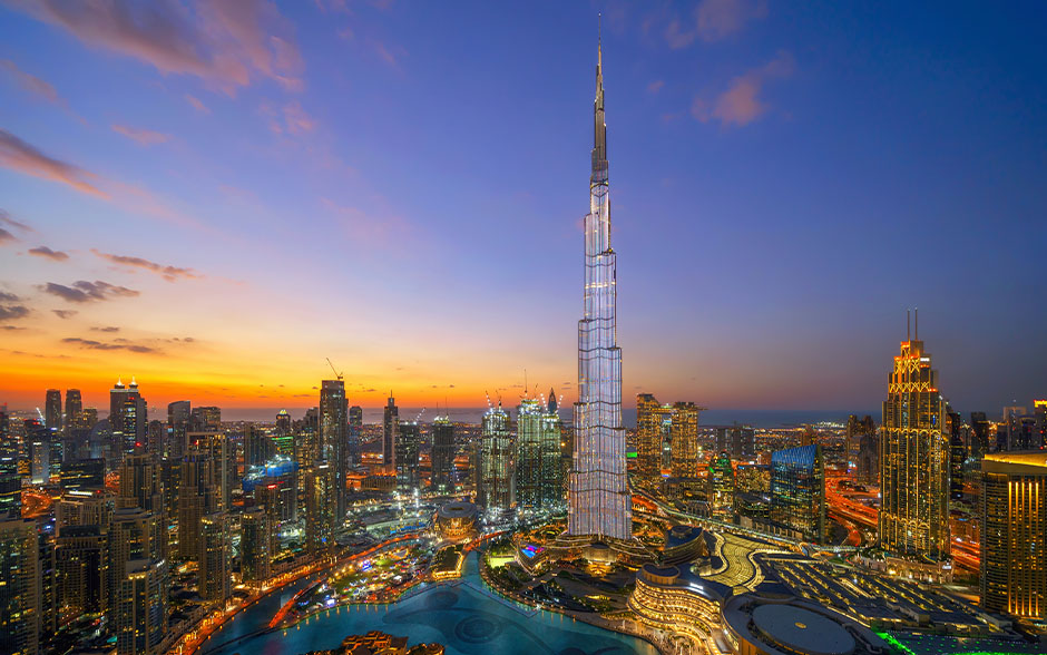 Dubai skyline at dusk with lights and sunset.