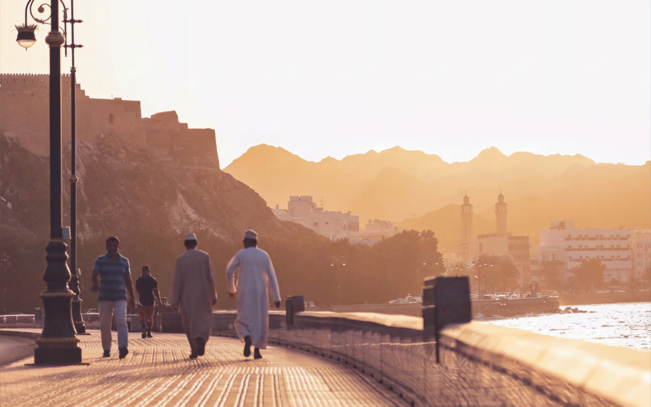 Men in white shirts walking on Muscat street in Oman.