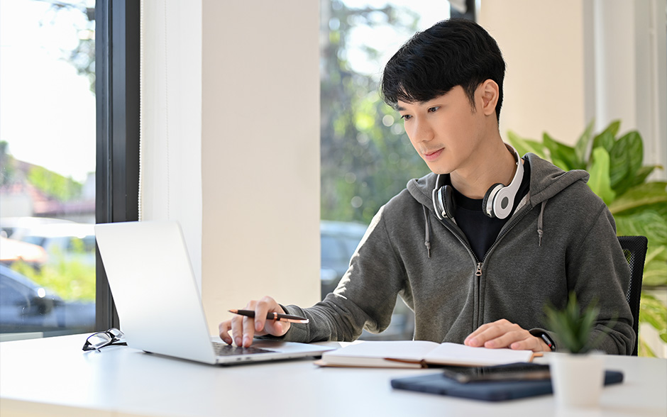A male Asian student using his laptop to review for an exam.