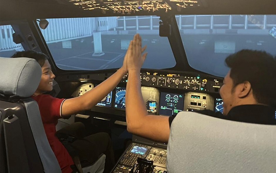 Two individuals in an airplane cockpit exchange a high five, surrounded by warm lighting.