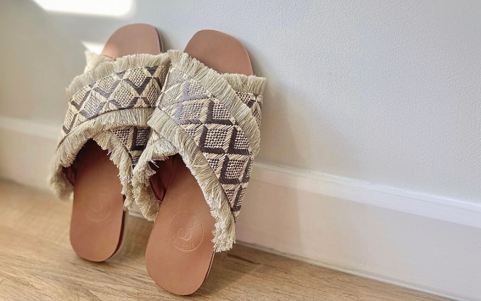 Locally made Sewn Sandals' slip-on sandals propped up against a wall.