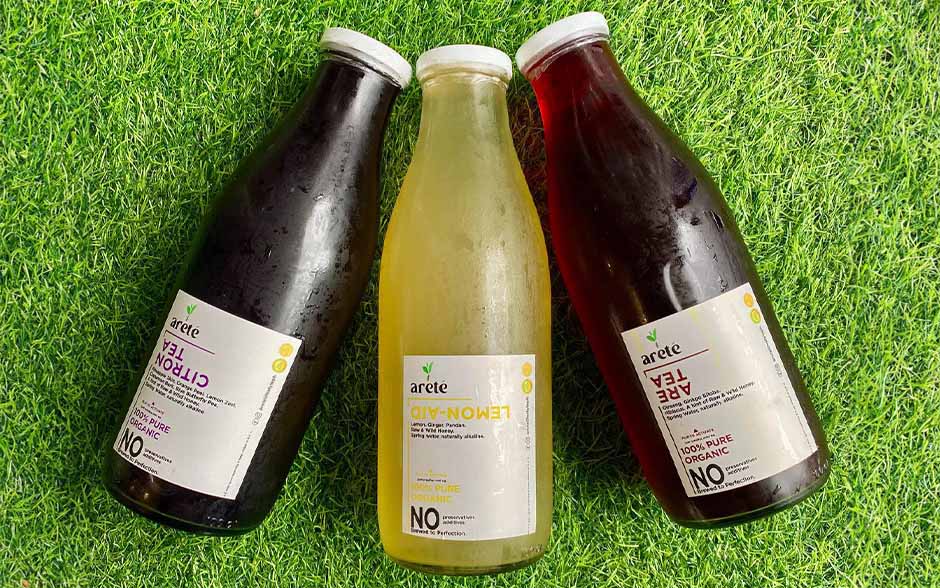 Three bottles of locally made Arete Lifestyle's fresh juices lying on the grass.