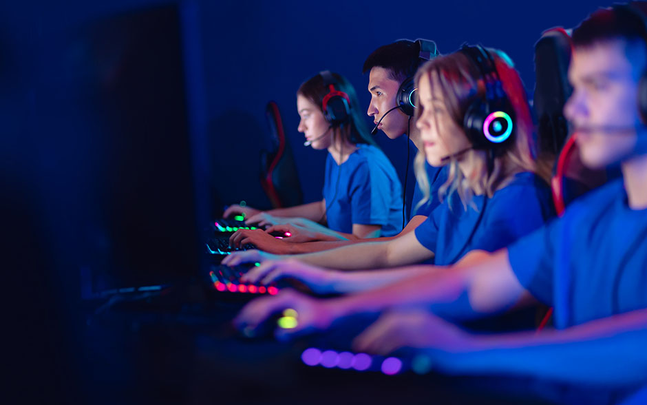 A focused team of young gamers wearing headsets plays together in an esports competition.