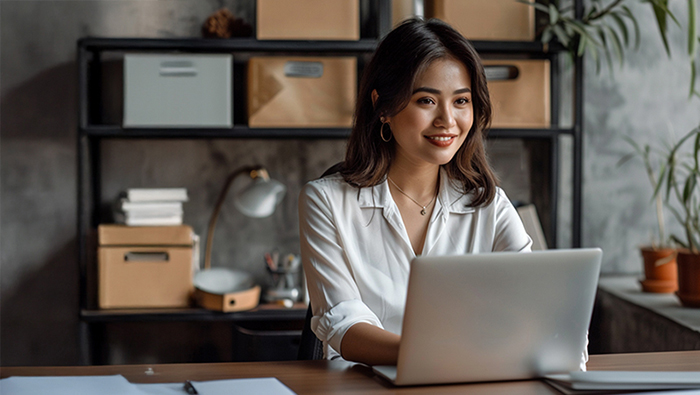 A professional woman in a blue blazer working on a laptop in an office.