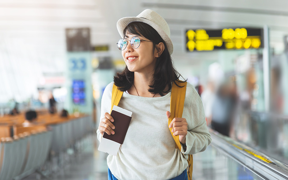 An asian tourist at the airport holding her passport and backpack before her flight