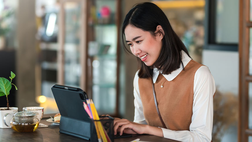 A smiling woman using her tablet for work.