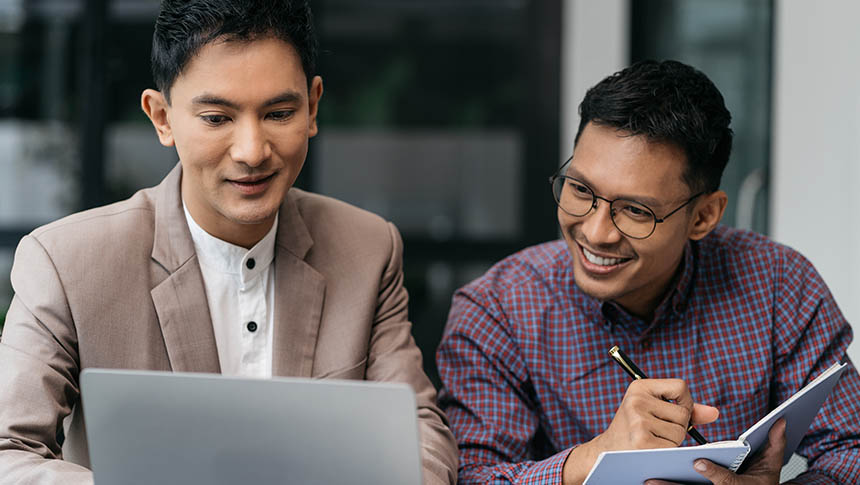 Two male professionals working together while using a laptop.