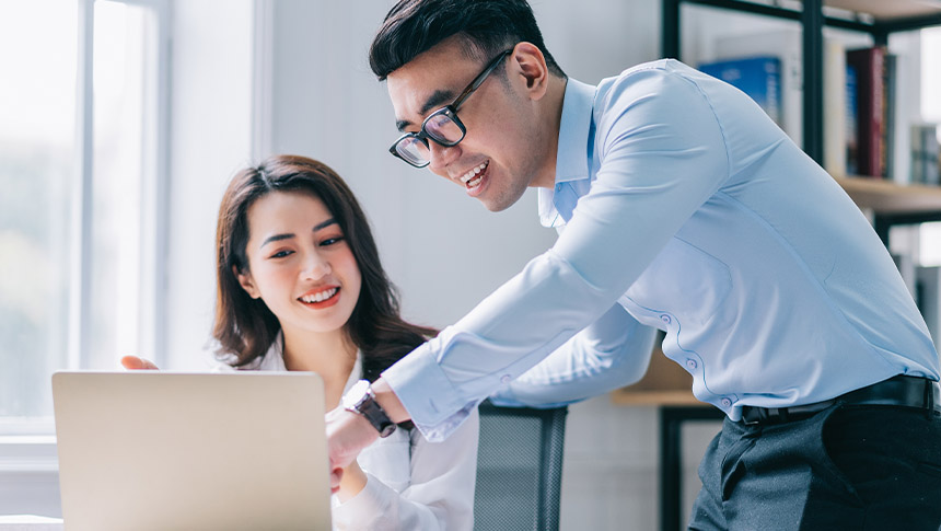 A male and female professional checking the laptop while at the office.