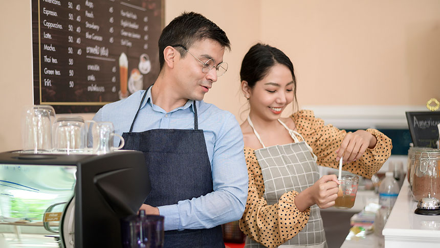 A male and female barista working at a cafe.