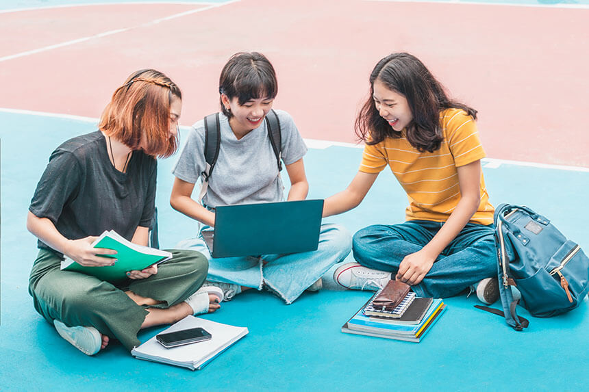 A group of students sitting in a school field, studying together.