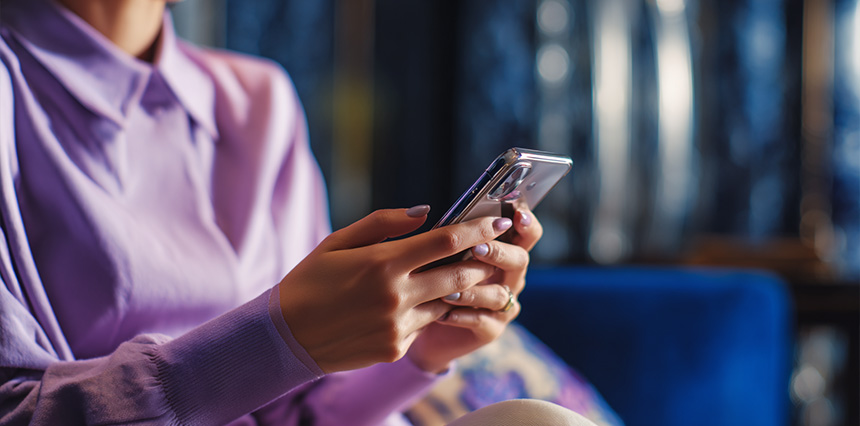 Close-up of a person sitting on a couch and holding a smartphone.