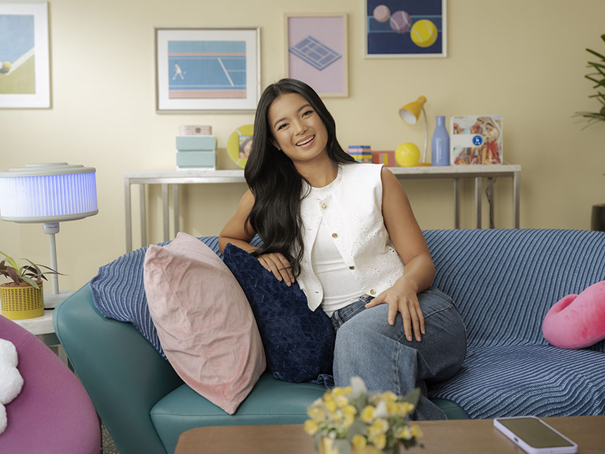 Alex Eala smiling while sitting on a couch during an interview.