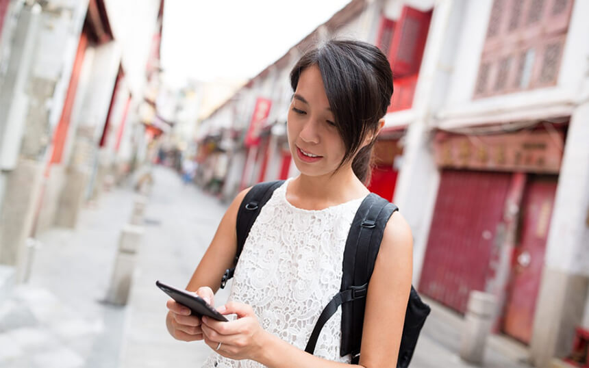 Woman uses phone while walking down an alley.