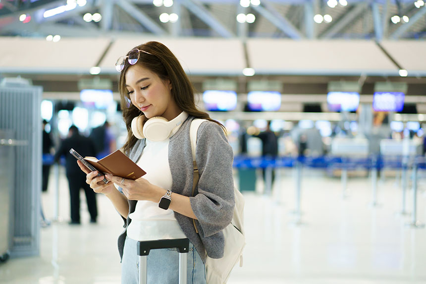 A young woman with a backpack and holding her passport and boarding pass in an airport.