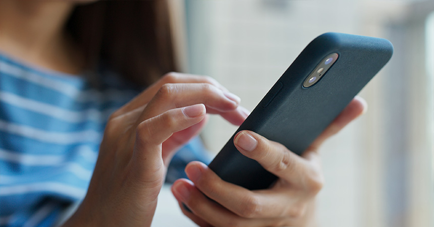 A woman holding and using a smartphone.