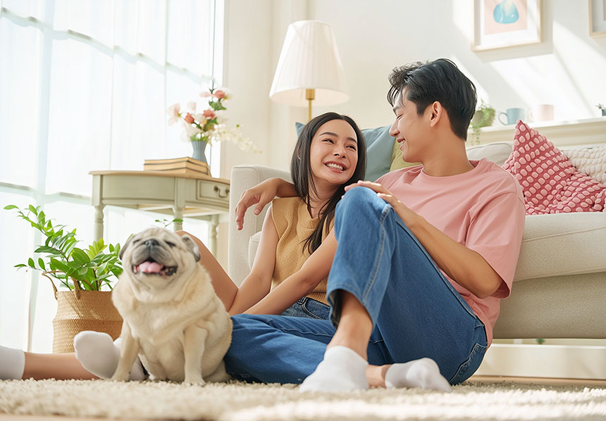 Young couple sitting on the floor in their living room, use natural light instead of electricity to save money.