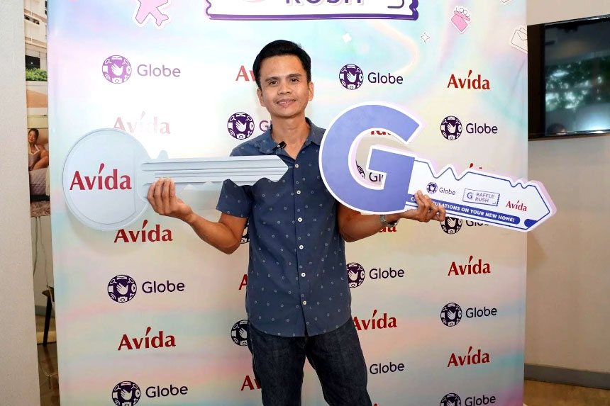 Resty Trinidad, G Raffle Rush 2024 condo winner, holding two big cardboard keys from Avida and Globe.