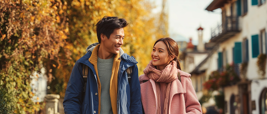 Couple walking together with autumn leaves in the background.