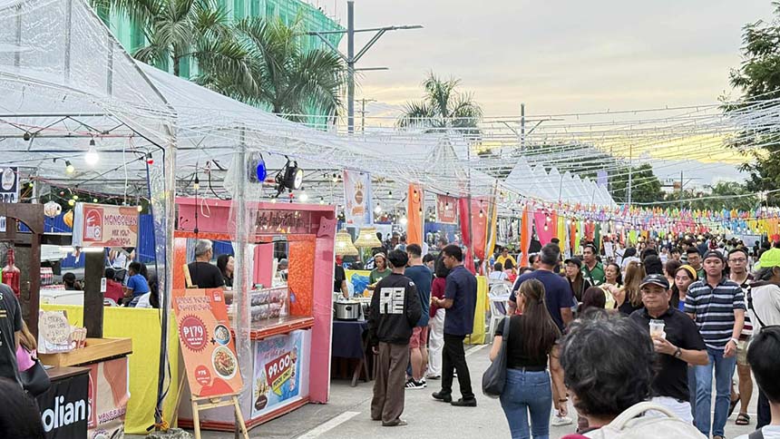 Crowds of people walking and exploring food stalls along Lacson Street in Bacolod City during a lively outdoor market or festival.
