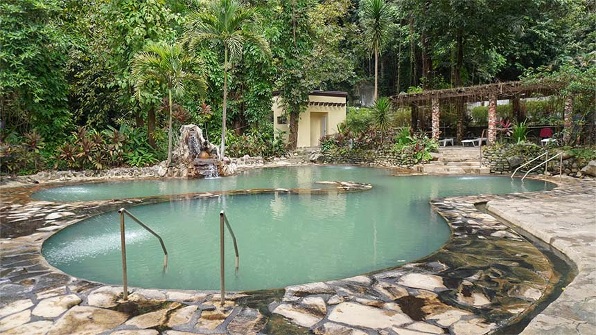 A hot spring pool surrounded by tropical plants and trees at Mambukal Resort & Wildlife Sanctuary in Negros Occidental.