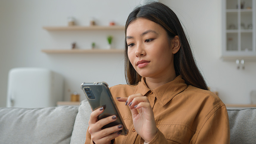 A young Asian woman holding her smartphone settings to check connectivity.