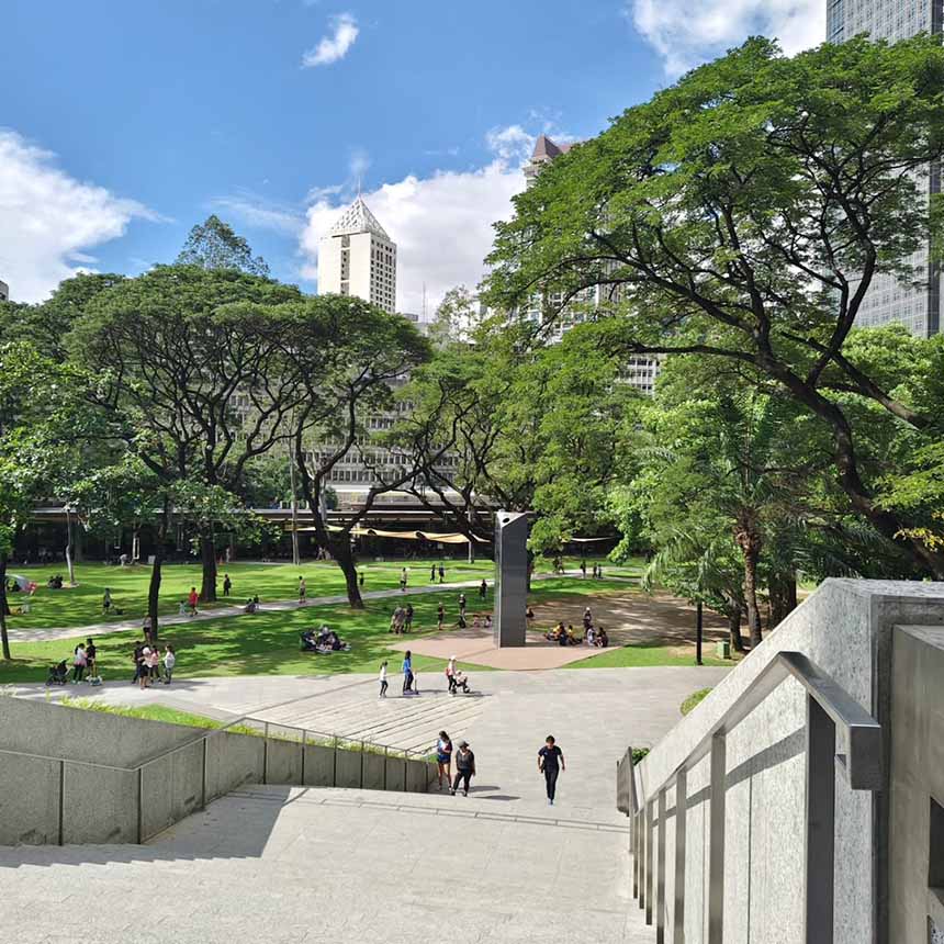 A green city park with open lawns and shaded paths where people and their pets enjoy outdoor time together.