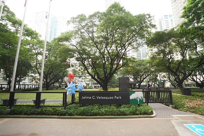 Entrance sign of Jaime C. Velasquez Park surrounded by trees and greenery in Makati.