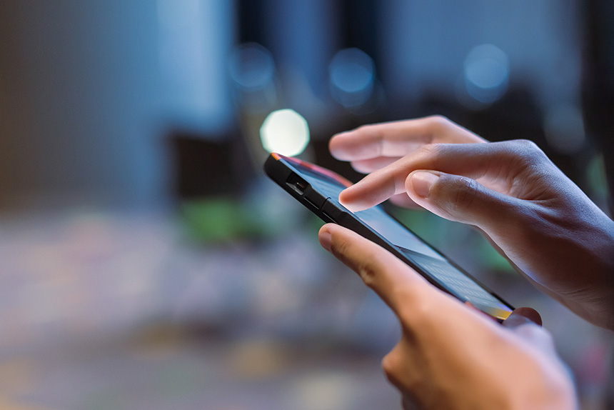 A womanâs hand taps on a smartphone with a WiFi icon above.