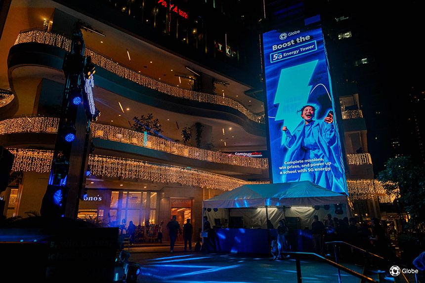 Globe 5G Energy Tower displayed on a large outdoor LED screen at Uptown Mall, BGC at night.