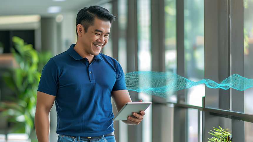 Smiling man in a blue polo shirt holding a tablet.