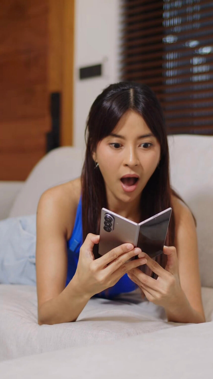 Bianca Gonzalez lying on a couch while using a foldable smartphone.