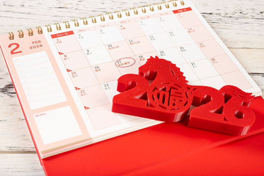February 2026 calendar with Chinese New Year date circled and red Year of the Horse decoration placed on top.