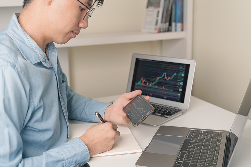 A man checking trading graphs and charts on his cellphone.