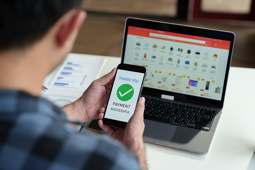 A man holding a phone with the screen showing the successful payment for a purchase.