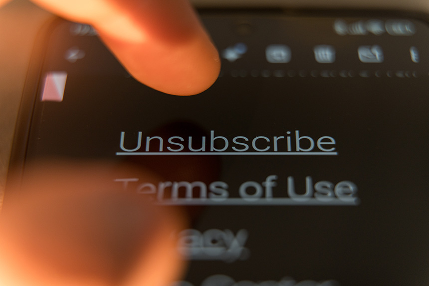 A finger tapping an unsubscribe button on a mobile app.