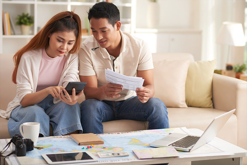 AÂ&nbsp; couple relaxing on a sofa, engaged with a mobile phone and laptop in their cozy living room.