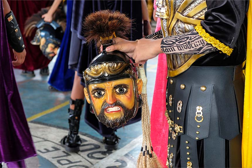 Moriones Festival participant in Roman costume holding a painted mask in Marinduque.